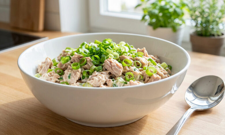 Bol de salade de thon et oignons verts. Thon émietté, sauce crémeuse et oignons verts frais sur un comptoir de cuisine.