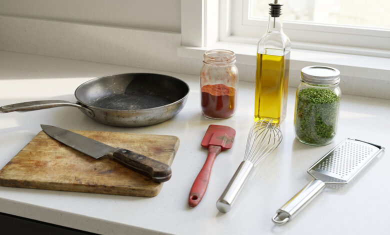Vue rapprochée d'un comptoir de cuisine avec divers ustensiles usagés et ingrédients : huile, épices et herbes. Lumière naturelle.